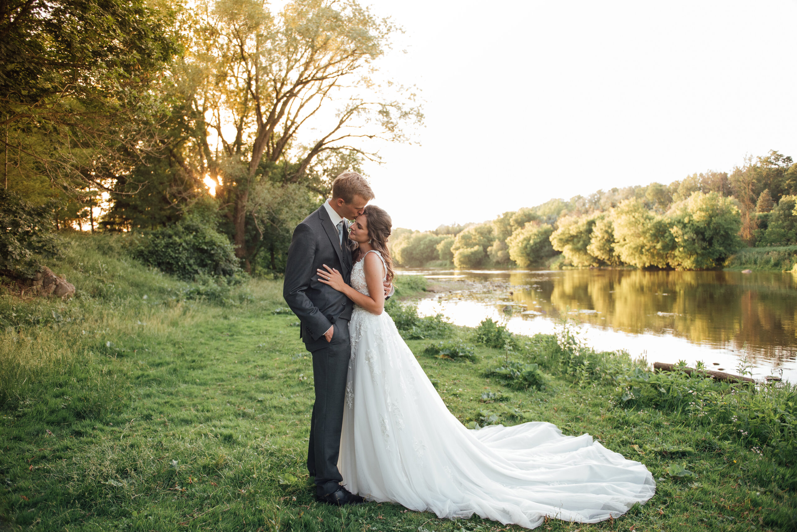 Bride and groom posing by the Grand River at Cellar 52 St. Jacobs during golden hour.